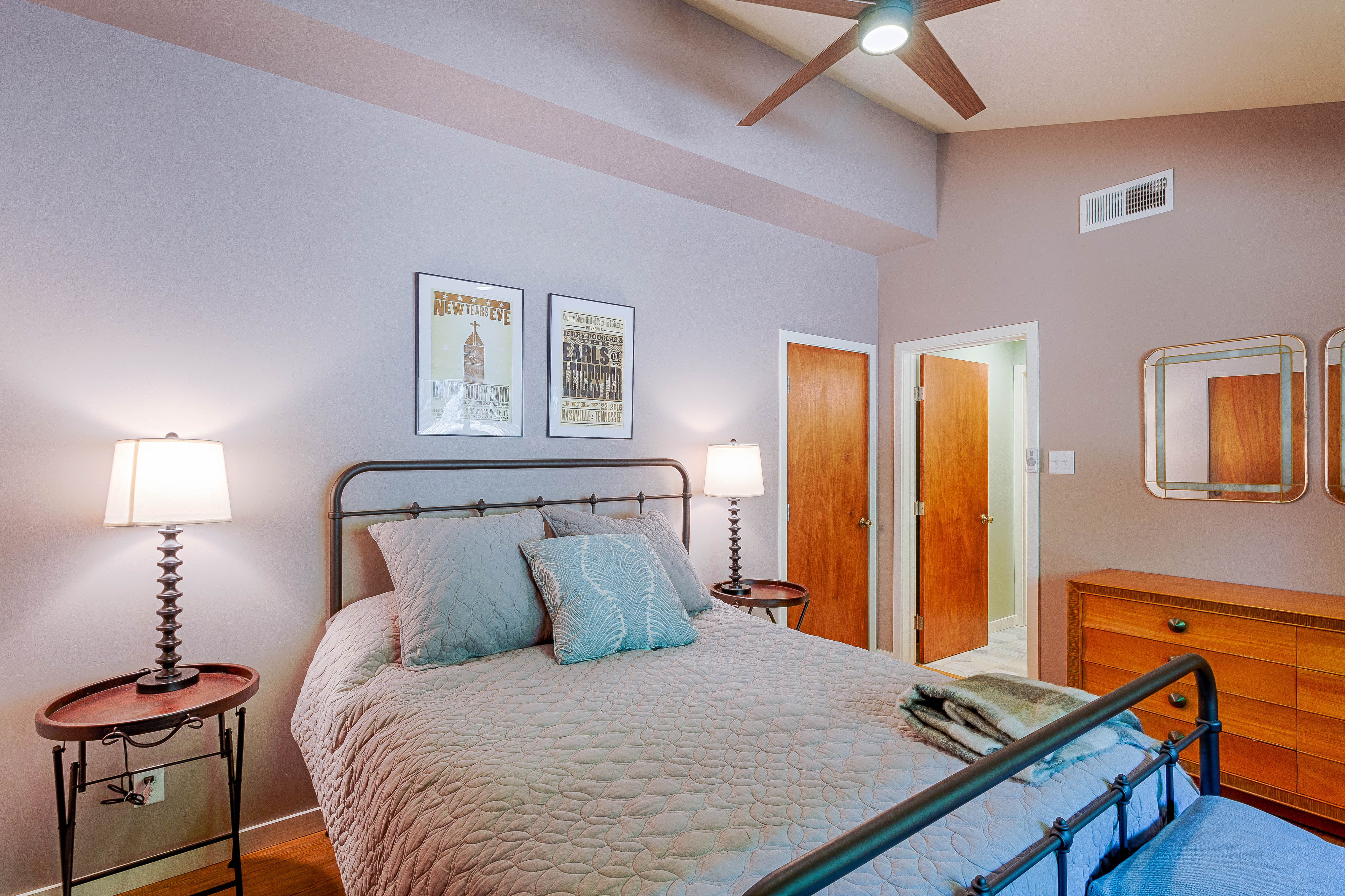 A calm bedroom with a quilted bed and doors toward the trees